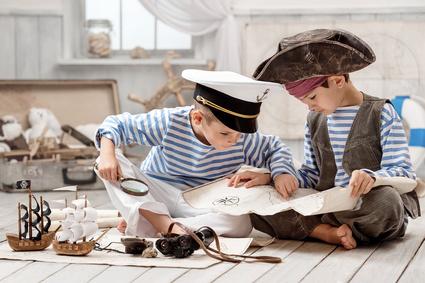 Boys dressed as a pirate captain and read travel map Hinterbliebenenvorsorge